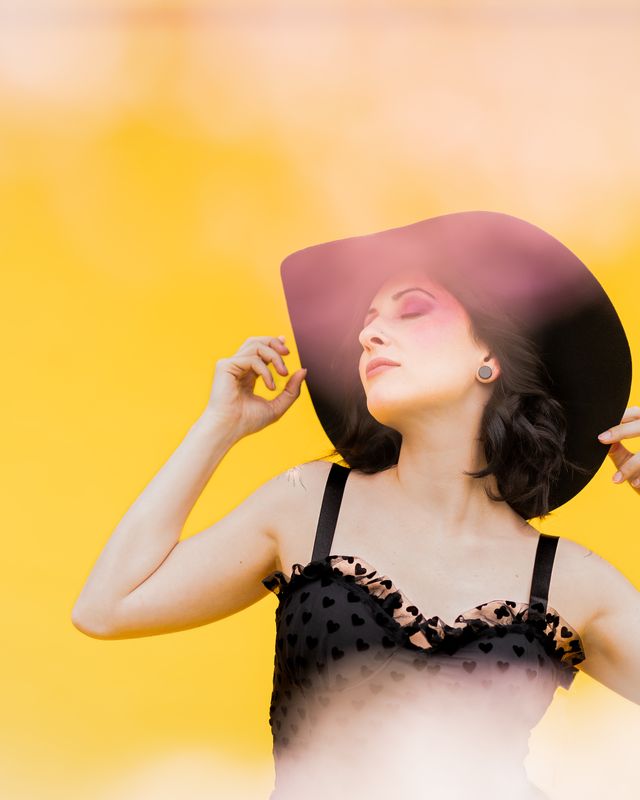 Portrait mit großem Hut vor gelbem Hintergrund