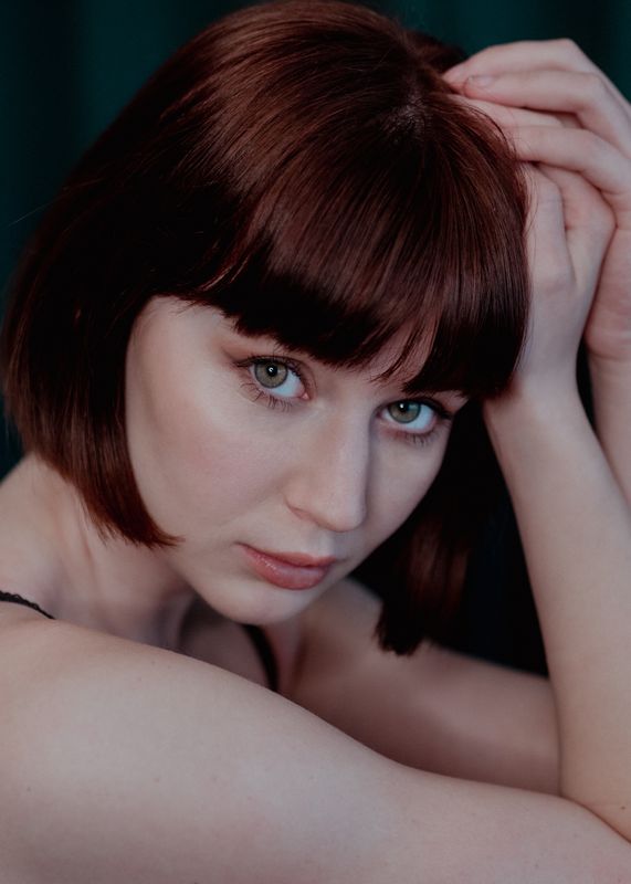 Portrait einer Frau mit rotbraunem Bob vor dunklem Vorhang, Make-up und Foto von Manu